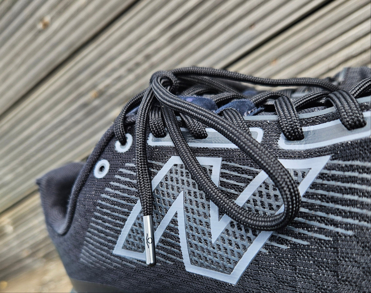 Gray athletic shoe with brand logo on a wooden surface