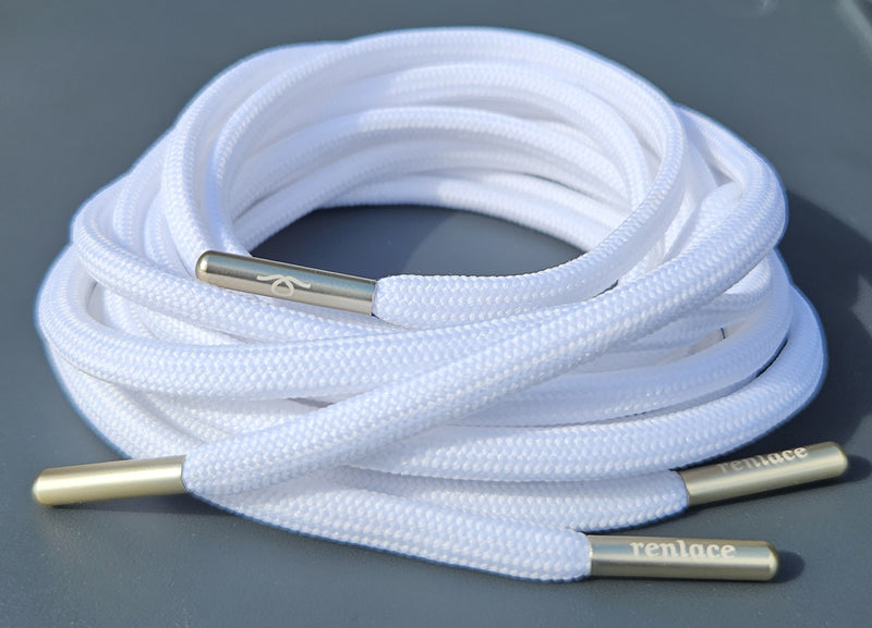 Coiled white shoelaces with gold metal tips on a gray backgroundN°01 Slim Trainer Lace in Black // Gun Metal