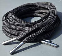 Coiled black shoelaces with silver metal tips on a gray surface replacement trainer lace — image 4