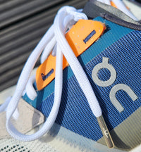 Close-up of a shoe with a blue strap and 'oc' branding on a wooden surface replacement trainer lace — image 3